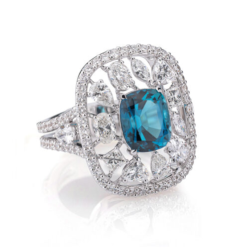 Anello in oro bianco 18kt, impreziosito da due gocce di diamante e diamanti taglio brillante incastonati sul gambo. Al centro una tormalina della Namibia di colore azzurro intenso di ct2,63, circondata da una serie di diamanti multiforme (cuore, navette, ovali, princess e gocce)